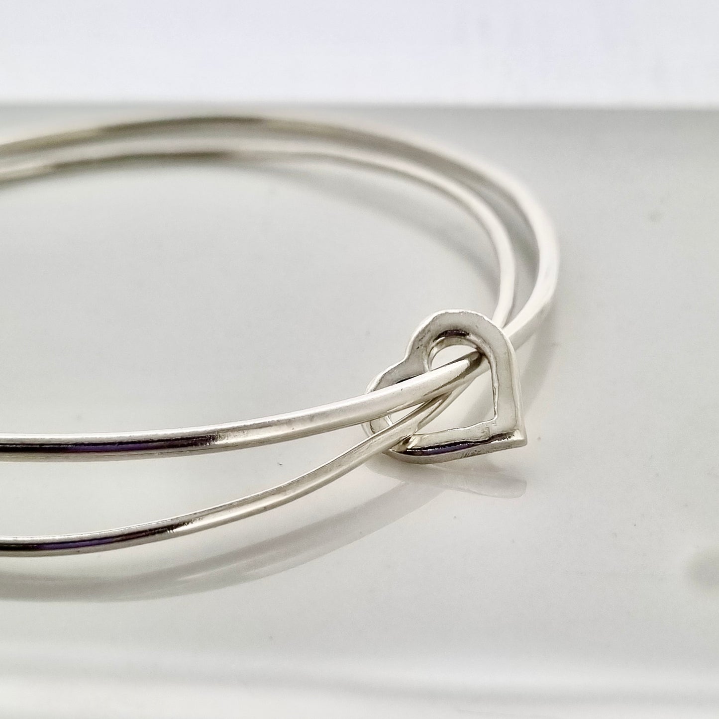 Linked by love - dual silver bangles connected by a silver or gold heart