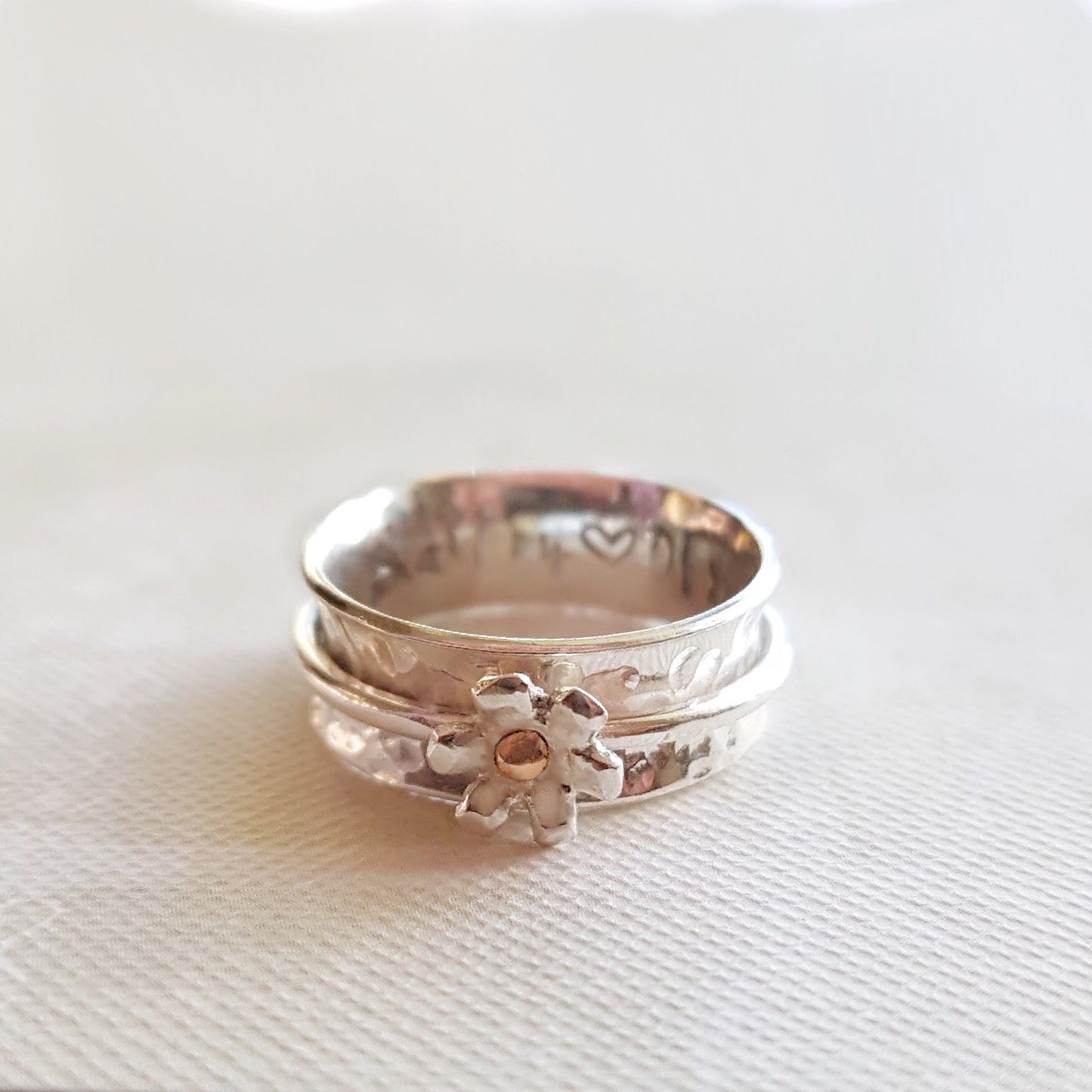 Silver daisy spinning ring with solid gold detail at its centre.