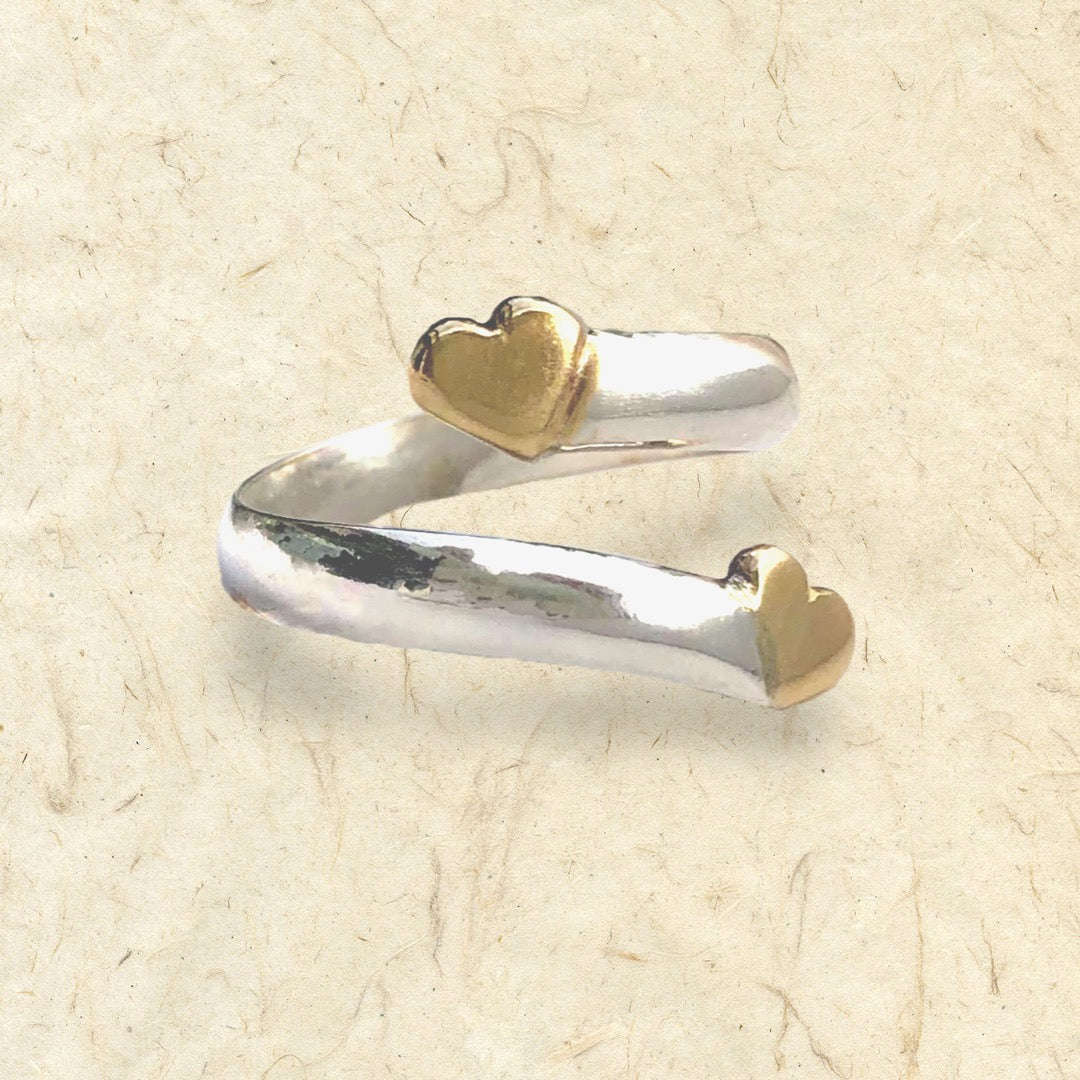 Solid silver twist ring with two gold hearts