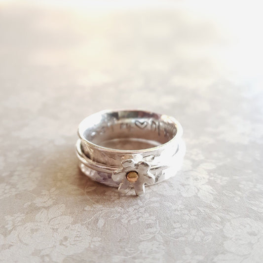 Silver daisy spinning ring with solid gold detail at its centre.