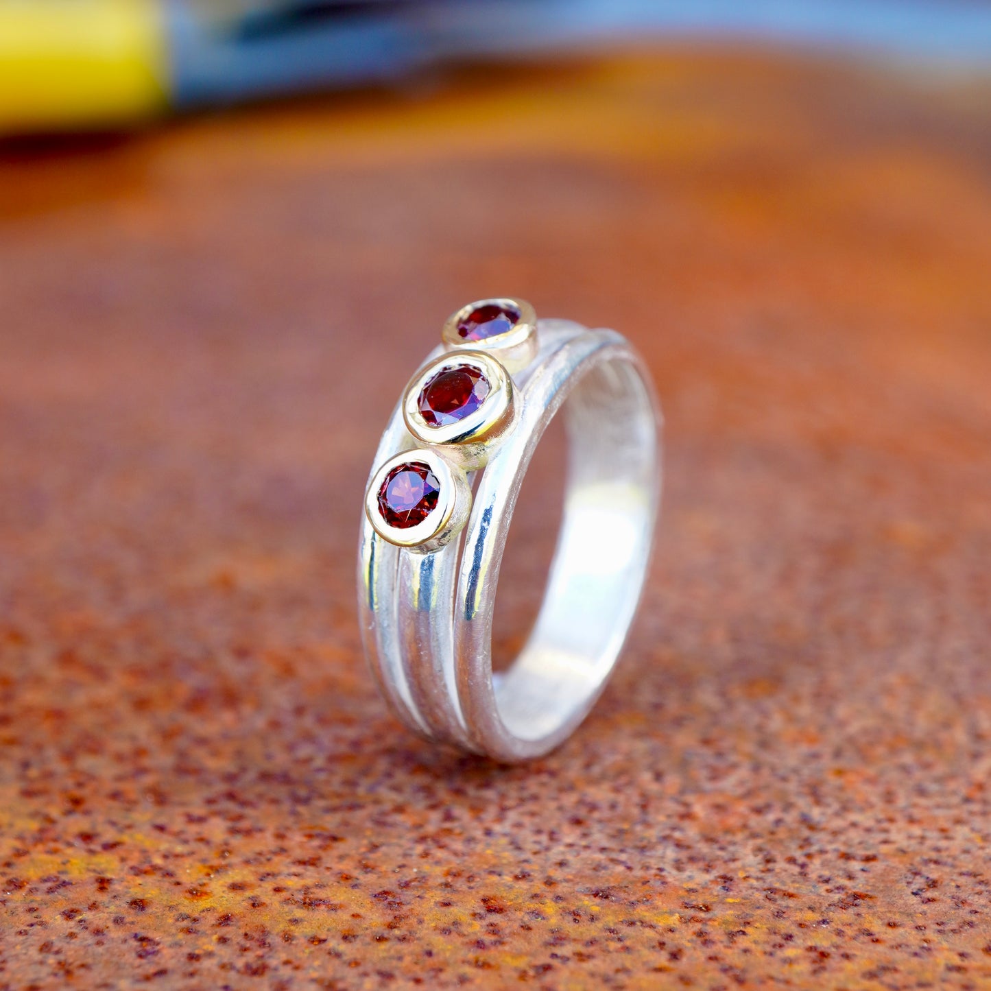 'Cariad lite' with garnets -  Crimson gemstones in gold settings on a sleek silver ring