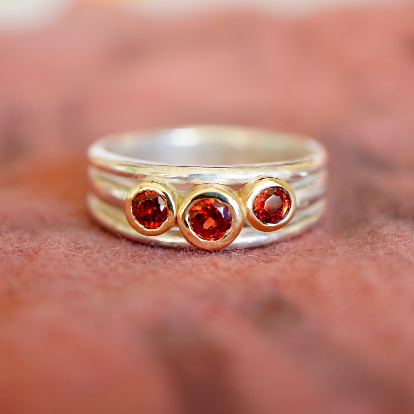 'Cariad lite' with garnets -  Crimson gemstones in gold settings on a sleek silver ring