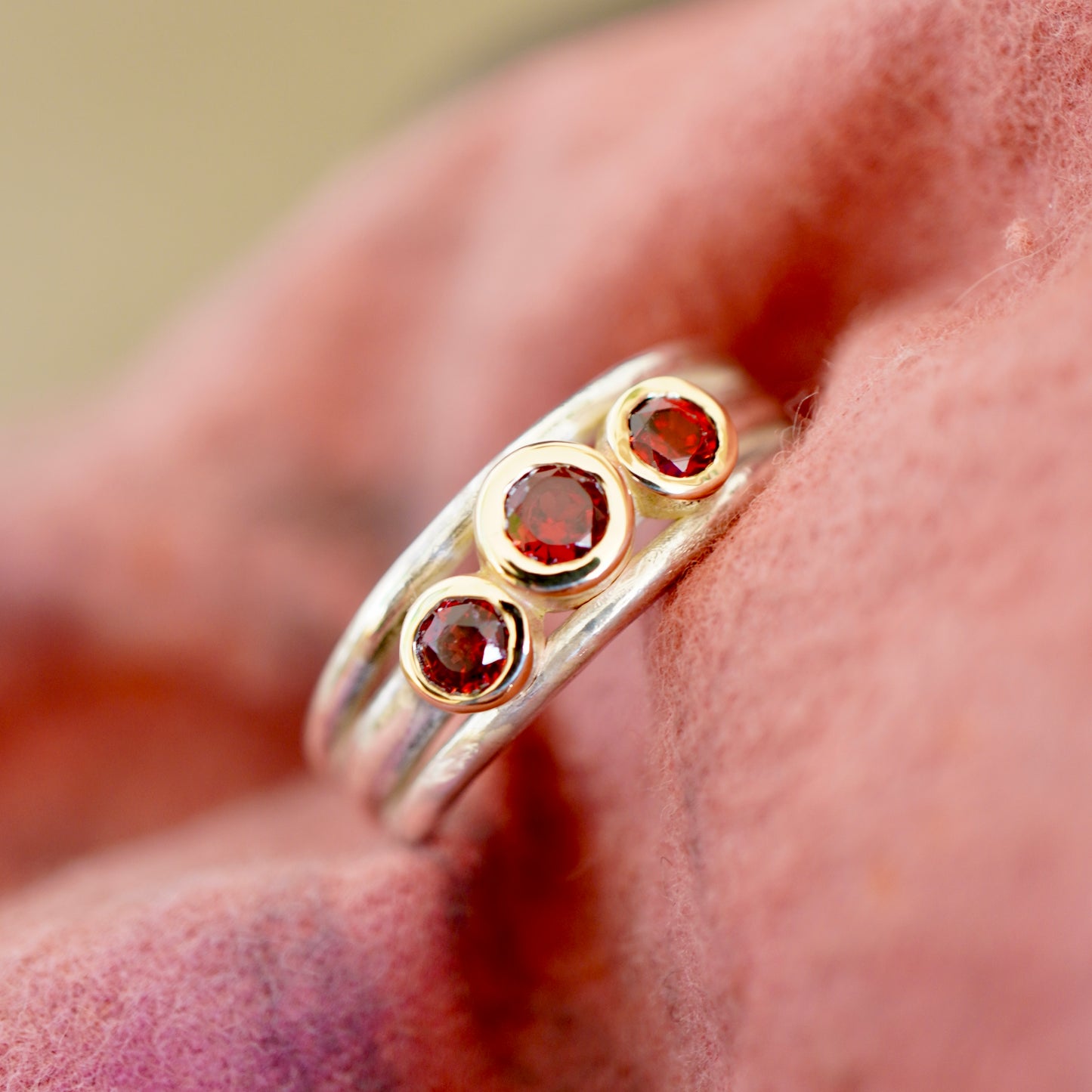 'Cariad lite' with garnets -  Crimson gemstones in gold settings on a sleek silver ring