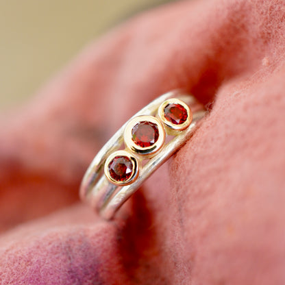 'Cariad lite' with garnets -  Crimson gemstones in gold settings on a sleek silver ring