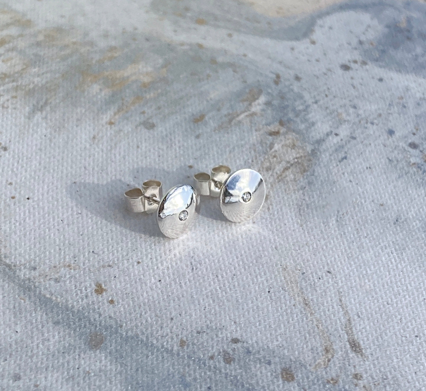 Domed silver earrings with diamonds.